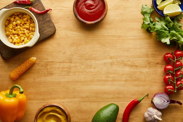 Vista superior de vegetais orgânicos com ketchup e mostarda em tigelas na superfície de madeira — Fotografia de Stock