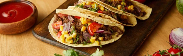 Delicious tacos with ketchup and vegetables on wooden background, panoramic shot — Stock Photo