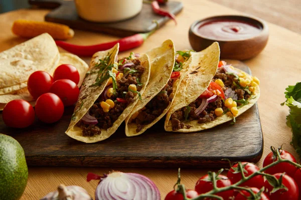 Fresh tacos with minced meat and vegetables on wooden table — Stock Photo
