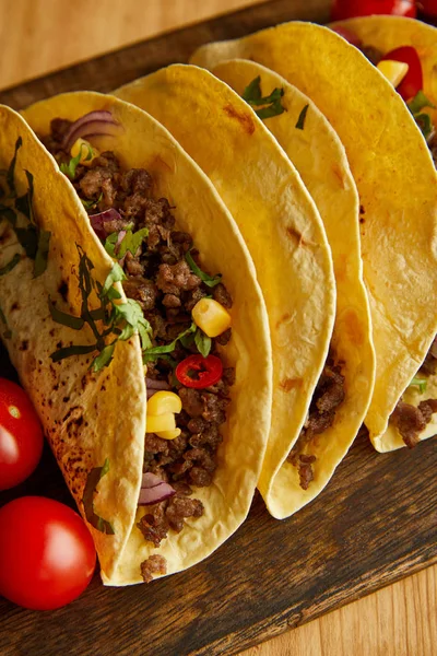 Vue grand angle des tacos aux tomates cerises sur planche à découper sur fond bois — Photo de stock