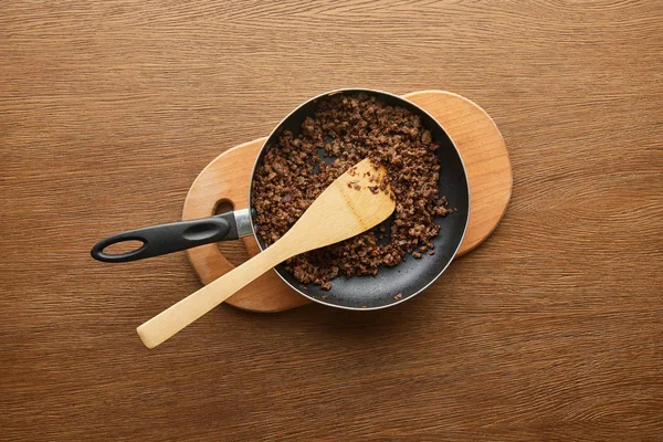 Top view of minced meat in frying pan on chopping board on wooden background — Stock Photo