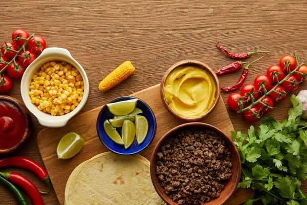 Vista superior de tortillas con ingredientes frescos sobre fondo de madera - foto de stock