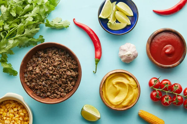 Vista dall'alto di verdure biologiche con salse e carne macinata su sfondo blu — Foto stock