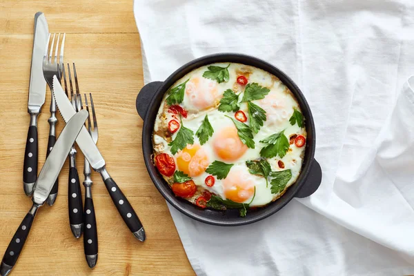 Top view of fried eggs on napkin near cutlery on wooden table — Stock Photo