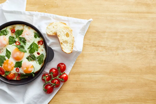 Spiegeleier in der Nähe von Brot und Tomaten auf Serviette auf Holztisch — Stockfoto