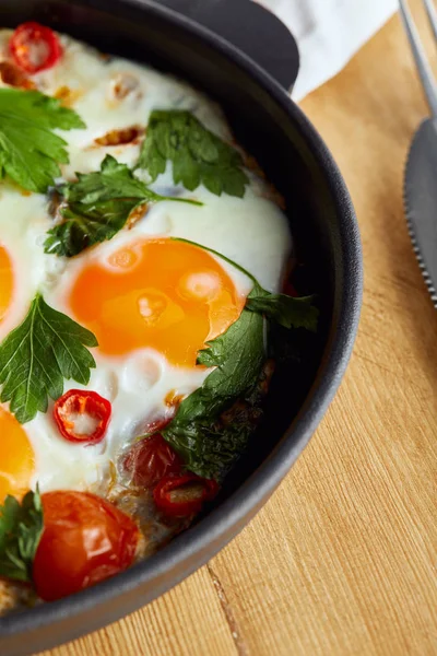 Close up view of fried eggs with parsley and chili pepper on wooden table — Stock Photo
