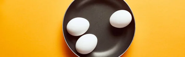 Top view of raw chicken eggs in frying pan on orange background, panoramic shot — Stock Photo