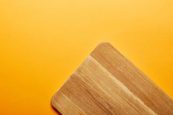 Top view of wooden cutting board on orange background — Stock Photo