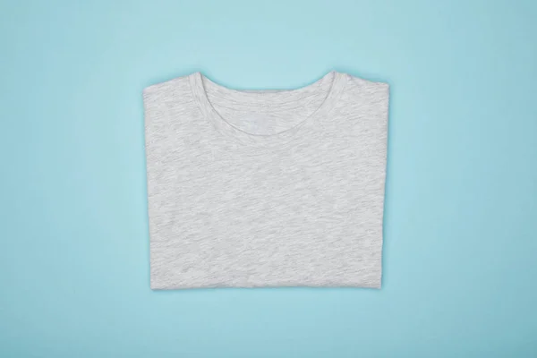 Vista superior de la camiseta gris básica en blanco aislada en azul - foto de stock