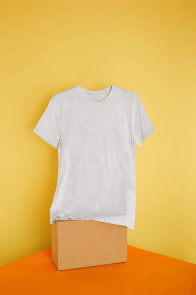 Basic grey t-shirt on cube on yellow background — Stock Photo