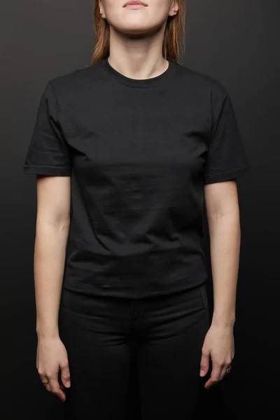 Vista ritagliata della donna in bianco di base nero t-shirt su sfondo nero — Foto stock