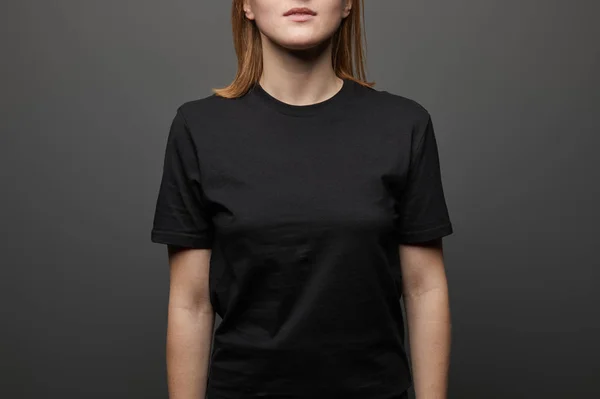 Cropped view of woman in blank basic black t-shirt on black background — Stock Photo