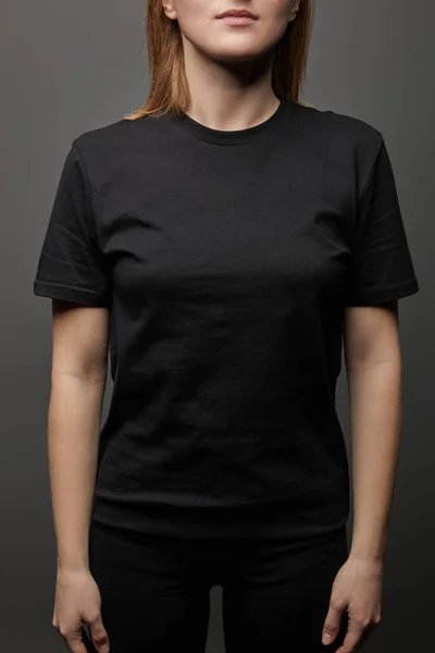 Vista ritagliata della donna in bianco di base nero t-shirt su sfondo nero — Foto stock