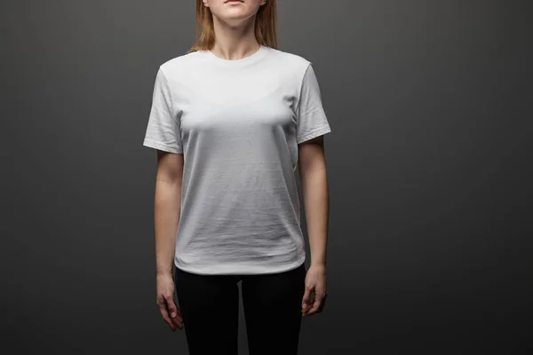 Vue recadrée de la femme en blanc blanc de base t-shirt sur fond noir — Photo de stock