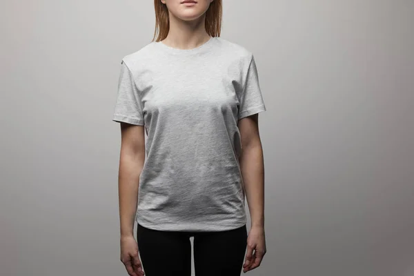 Cropped view of woman in blank basic grey t-shirt on grey background — Stock Photo