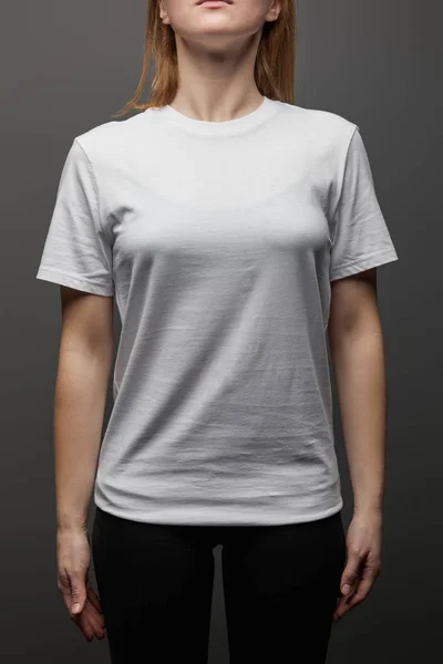 Vista recortada de la mujer en blanco básico camiseta blanca sobre fondo negro - foto de stock