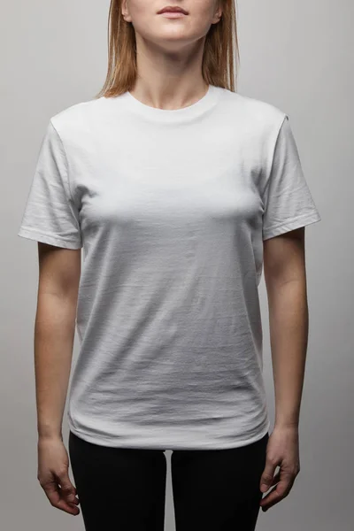 Vista recortada de la mujer en blanco básico camiseta blanca sobre fondo gris - foto de stock
