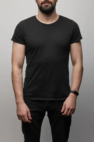 Cropped view of bearded man in blank basic black t-shirt on grey background — Stock Photo