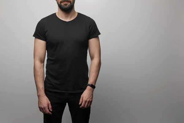 Cropped view of bearded man in blank basic black t-shirt on grey background — Stock Photo