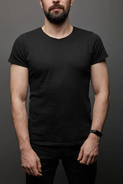 Cropped view of bearded man in blank basic black t-shirt on black background — Stock Photo