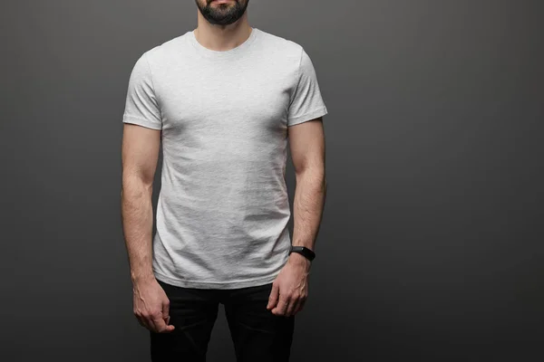 Обрезанный вид бородатого человека в пустой основной серой футболке на черном фоне — Stock Photo