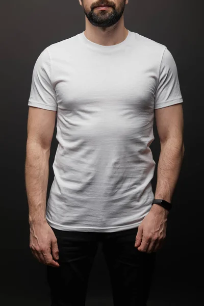 Vue recadrée de l'homme barbu en blanc blanc de base t-shirt isolé sur noir — Photo de stock