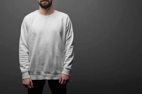 Cropped view of bearded man in blank basic grey sweatshirt on black background — Stock Photo