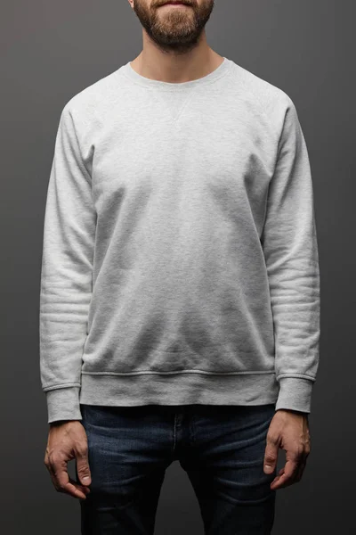 Cropped view of bearded man in blank basic grey sweatshirt on black background — Stock Photo