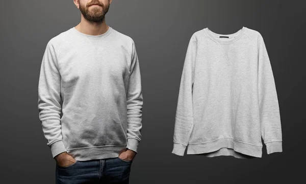 Cropped view of bearded man near blank basic grey sweatshirt on black background — Stock Photo