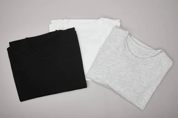 Top view of blank basic black, white and grey t-shirts isolated on grey — Stock Photo