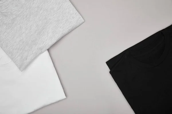 Vista superior de las camisetas básicas en blanco, negro, blanco y gris aisladas en gris - foto de stock