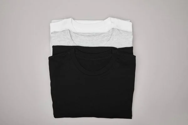 Top view of blank basic black, white and grey t-shirts isolated on grey — Stock Photo