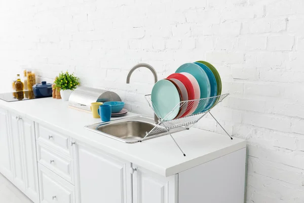 Intérieur moderne de cuisine blanche avec ustensiles de cuisine près du mur de briques — Photo de stock