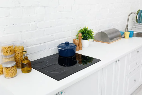 Intérieur moderne de cuisine blanche avec ustensiles de cuisine près du mur de briques — Photo de stock