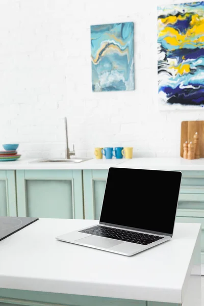 Enfoque selectivo de la computadora portátil con utensilios de cocina y pinturas abstractas en el fondo - foto de stock