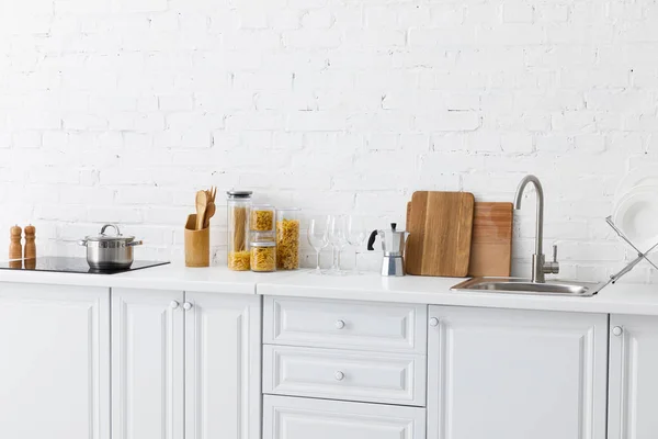 Intérieur moderne minimaliste de cuisine blanche avec ustensiles de cuisine près du mur de briques — Photo de stock