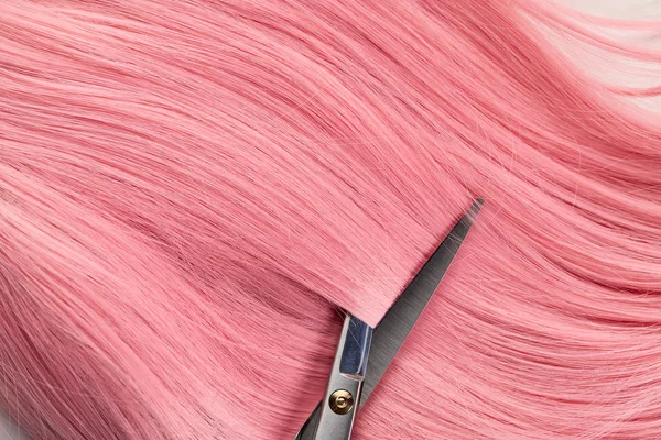 Top view of scissors and colored pink hair on white background — Stock Photo