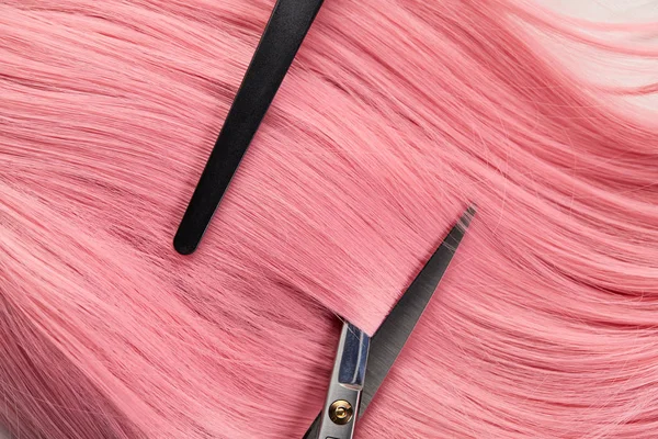 Вид сверху на клип и ножницы на цветных розовых волосах на белом фоне — стоковое фото