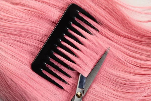 Top view of comb and scissors on pink hair on white background — Stock Photo