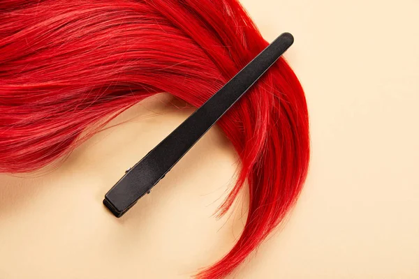 Top view of clip and colored red hair on beige background — Stock Photo