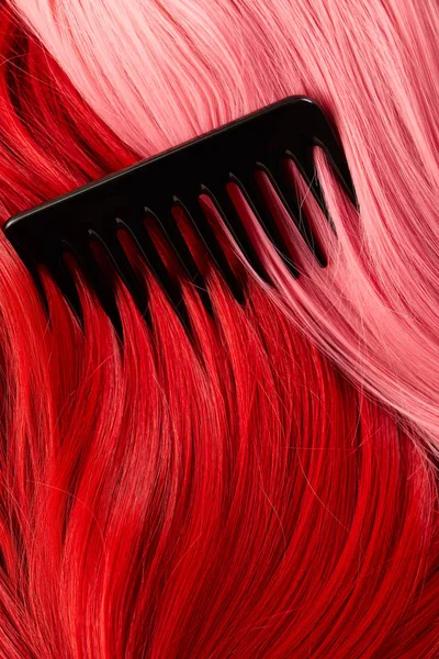 Top view of comb on colored pink and red hair — Stock Photo