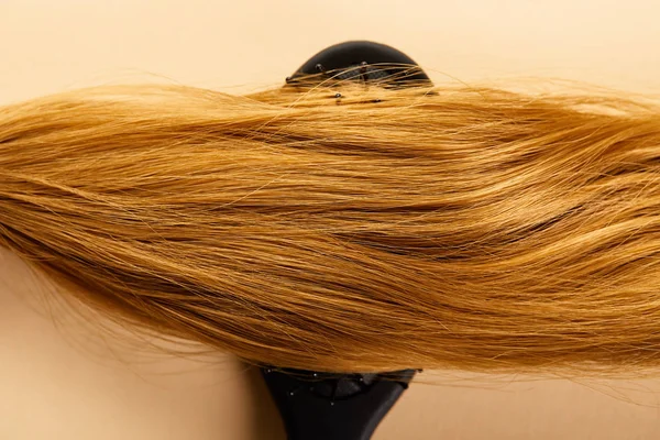 Top view of brown hair on hairbrush on beige background — Stock Photo