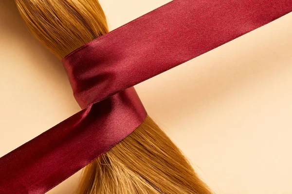 Draufsicht auf braune Haare mit Schleife auf beigem Hintergrund — Stockfoto