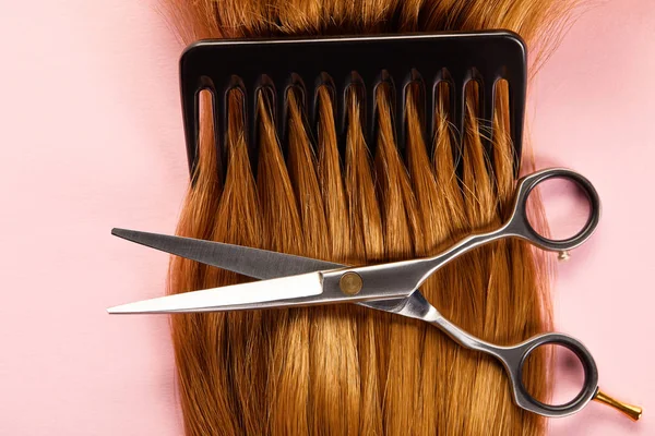 Top view of scissors, comb and brown hair on pink background — Stock Photo