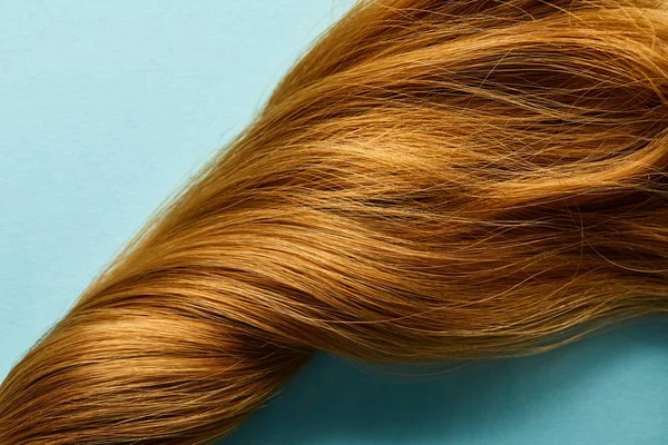 Vue de dessus des cheveux bruns tordus sur fond bleu — Photo de stock