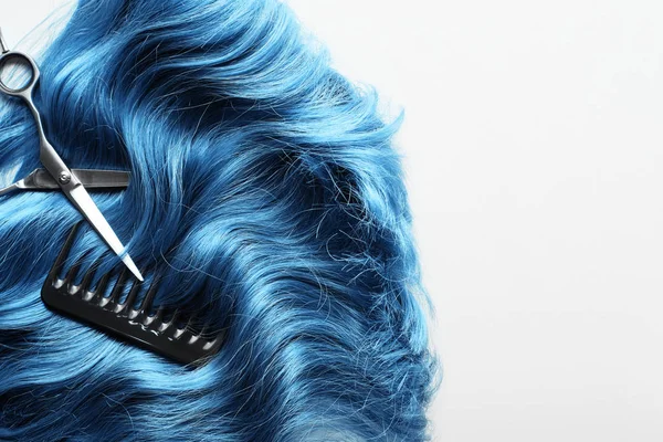 Vue de dessus des ciseaux et peigne sur cheveux bleus ondulés isolés sur blanc — Photo de stock