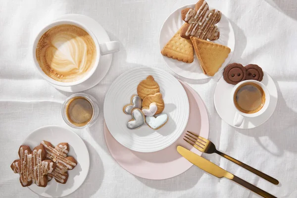 Vista dall'alto di caffè e biscotti sulla tovaglia bianca — Foto stock