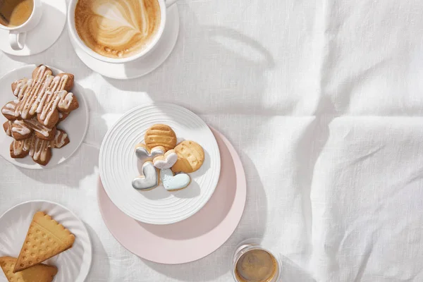 Vista superior de deliciosas galletas con café sobre tela blanca con espacio para copiar - foto de stock