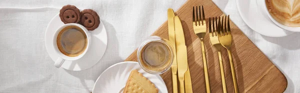 Top view of coffee and tasty cookies on chopping board on white cloth, panoramic shot — Stock Photo
