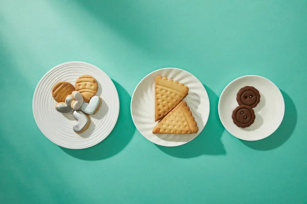Vue du dessus des biscuits savoureux sur assiettes sur fond turquoise — Photo de stock